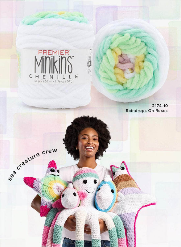 
The image features a promotional collage for Premier Minikins Chenille yarn. At the top, there are close-up views of a yarn ball labeled "Premier Minikins Chenille," showcasing soft pastel shades of green, yellow, and lavender, with the color name "Raindrops on Roses" (2174-10). Below, a smiling woman holds a collection of crocheted plush sea creatures made with the yarn, including an octopus, starfish, and other colorful marine animals. The phrase "sea creature crew" is displayed diagonally on the left. T